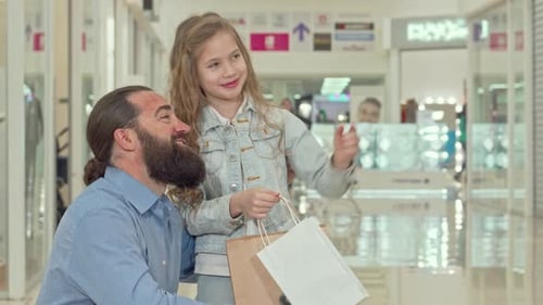 Little Girl Excitedly Pointing Out Something to Her Father in a Bustling Shopping Mall