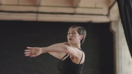 Woman Dancing Gracefully in Dark Studio Setting