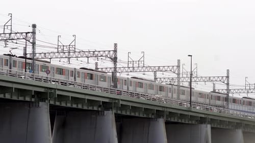A Long Train Passing By On The Railway On The Bridge In Tokyo, Japan - Low Angle Shot