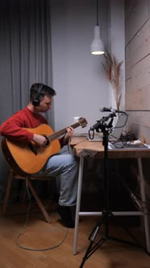 Man Playing Guitar at Desk in Studio