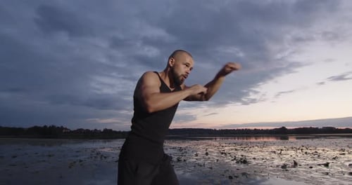 Man Shadow Boxing at Lakeside Sunrise