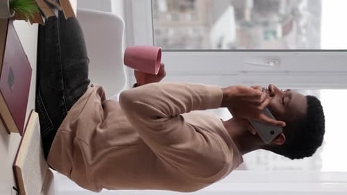 Man Talking on Phone with Coffee at Desk