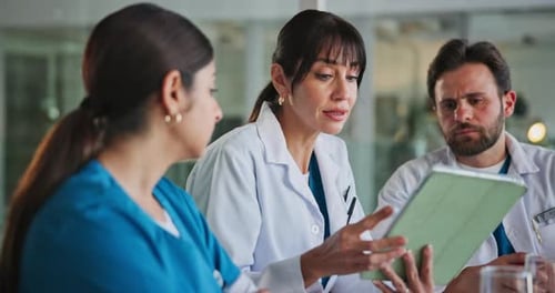 Medical Professionals Discussing Data on Tablet in Hospital