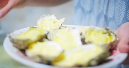 Oysters on Plate Being Held Close Up