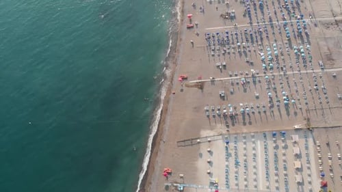 Bird's eye view of a sandy beach with sunbeds and umbrellas