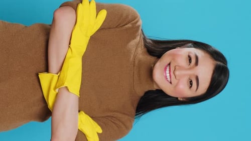 Young Woman Smiles Wearing Cleaning Gloves in Studio