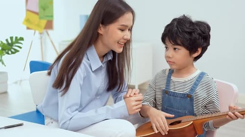 Teacher Helping Child Learn Ukulele in Classroom