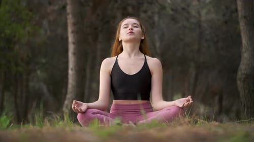 Redhead Young Woman Meditating in a Forest