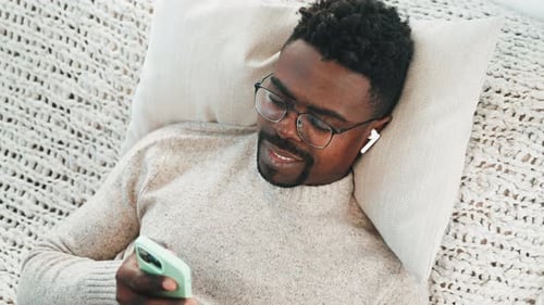 Smiling Young Adult Resting with Cellphone Indoors