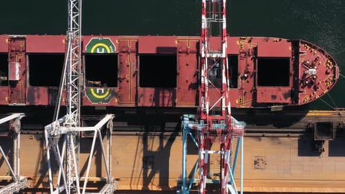 Top View of Three Cranes Unloading a Tanker with Black Coal