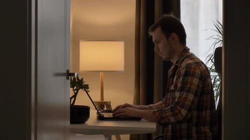 man works at his laptop at table at home