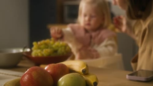 Infant Eating Grapes with Blond Hair and Mother