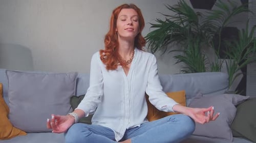 Woman Meditating on Couch in Bright Living Room