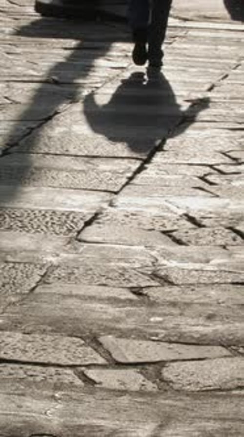 People Walk Along Stone Street on Sunny Day