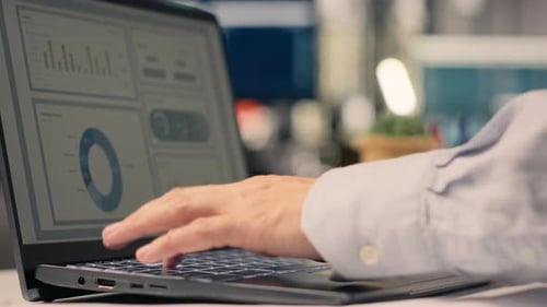 Typing on a Laptop with Data Analytics Displayed