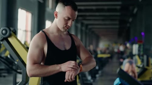 Muscular Man Checking Smartwatch During Gym Workout Session