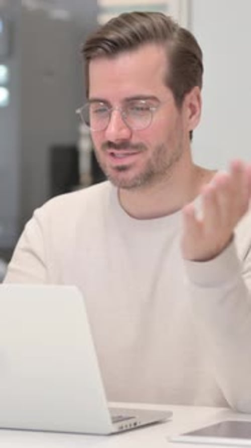Young Man Doing Video Chat on Laptop in Office