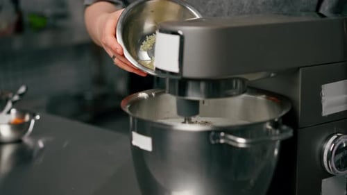 Backer in a Professional Kitchen Over an Iron Table Baker Pours Gelatin Into a Mixer