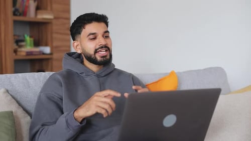 Man Talking on Laptop on Sofa at Home