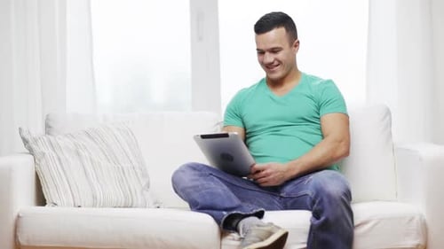Man Using Tablet Relaxing on White Couch at Home
