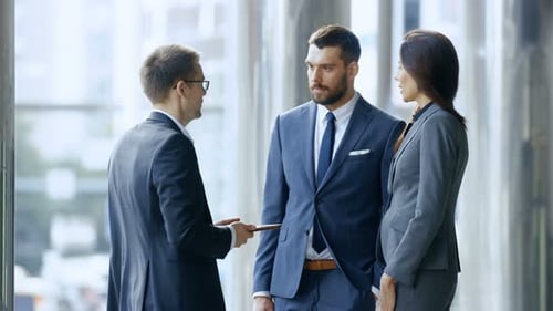 Hombres y mujeres de negocios usan tabletas y discuten ideas de inversión mientras están de pie