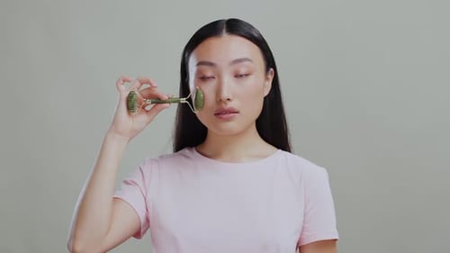 Young Woman Using Jade Facial Roller for Beauty