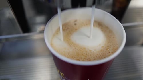 Slowmo close up of coffee machine pouring a cappuccino into the cup