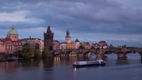 Day to night sunset timelapse with a close up view of Charles Bridge on Vltava river with boats on a