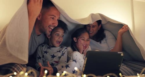 Family Gathers Under Blanket Watching Tablet at Night