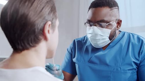 Afroamerikanischer Arzt führt im Krankenhausbüro einen Coronavirus-Test durch: Mediziner und Patient