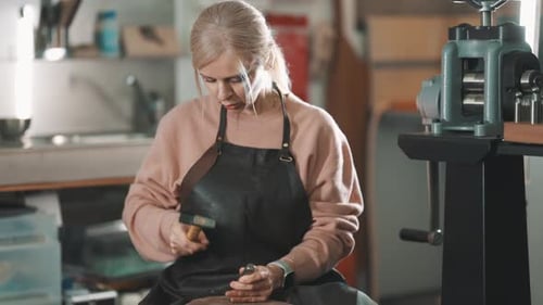 Focused Female Jeweler Crafting Metal with Hammer