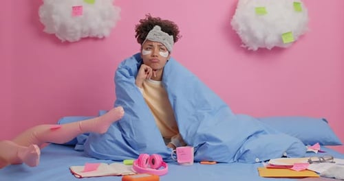 Woman Wrapped in Blanket Sits Among Messy Papers