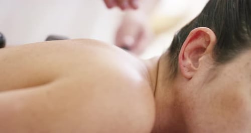 4k video of a young woman enjoying a hot stone treatment at a spa