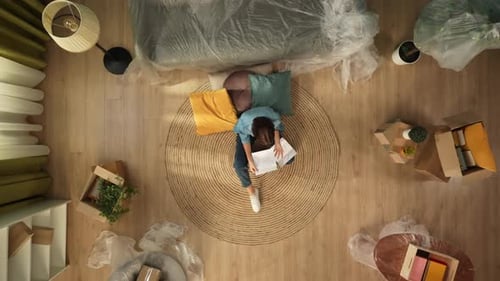 Top View of Apartment Living Room Woman Sitting on the Floor Reading Eviction Notice Papers Looking