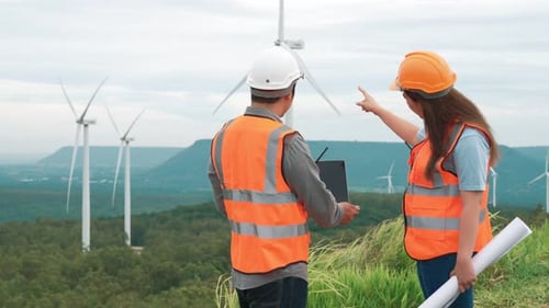 Progressive Concept of Engineers Working in the Wind Farm Atop of the Mountain