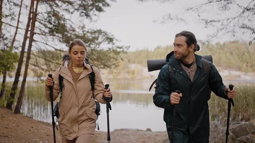 Young Couple Enjoying Nordic Walking Near Lake and Forest