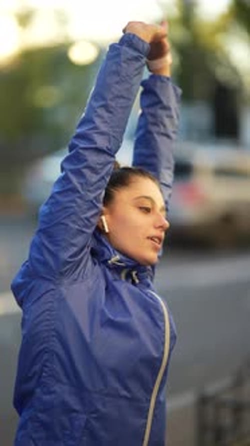 Woman Stretching Arms Overhead in Urban Park