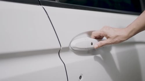 Woman's hand opens white car door. Woman opens car door. Business woman opening car door, holding ha