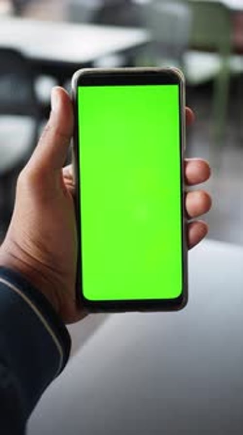 A Hand Holds a Smartphone Showing a Bright Green Screen Ideal for Customization