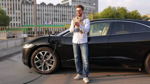 Mann benutzt Telefon am Elektrofahrzeug