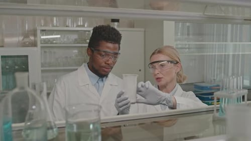 Diverse Chemists Examining Substance in Measuring Cup