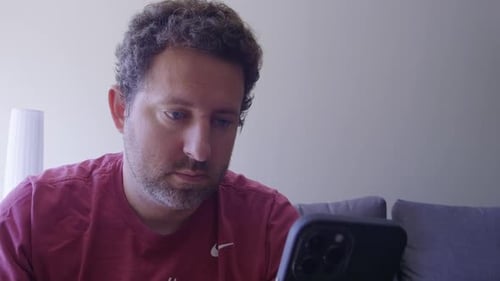 A close up shot of a man taking rest on sofa at home look at cellphone screen texting or messaging.
