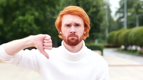 Man Gives Thumbs Down Gesture in Outdoor Setting