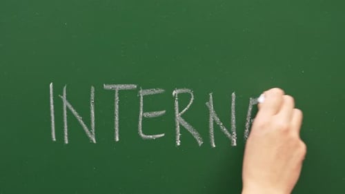 A Hand Writes Internet On A Green Chalkboard