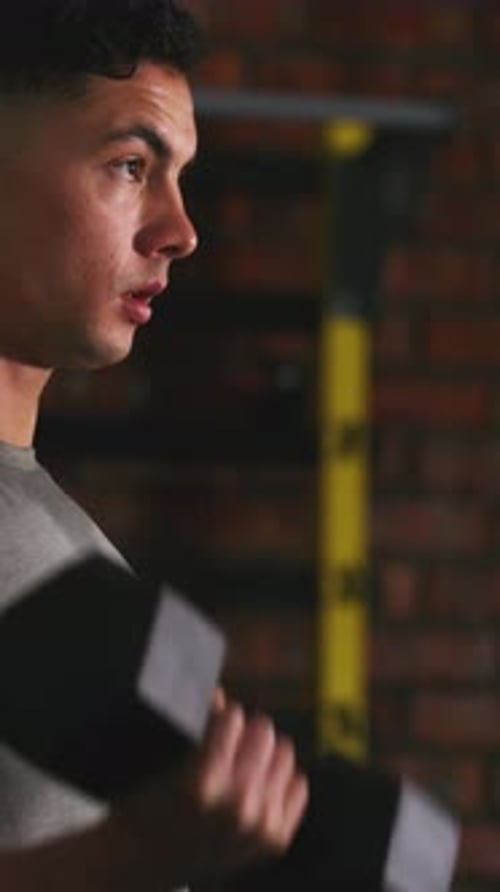 Man, serious and dumbbell in gym for weightlifting, arm muscle development and strength training