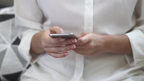 Adult Hands Typing on Mobile Phone Indoors