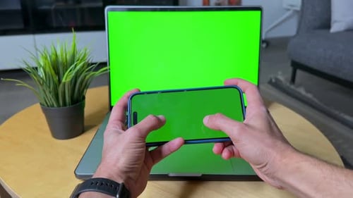 4K Green Screen Mockup of Hands Holding Smartphone in Front of Laptop