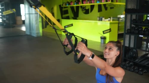 Young Athletic Woman Doing Exercises with Trx Fitness Straps in the Gym