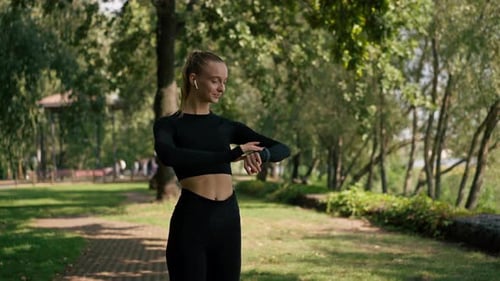 Sporty girl during a morning jog in the park looks at the sports watch on her hand to determine