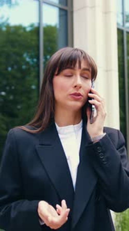 Young Brunette Caucasian Businesswoman in Black Blazer Standing in Front of a Modern Glass Office